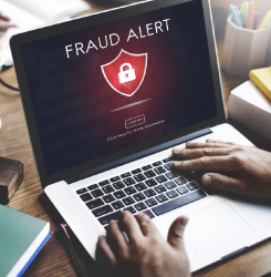 Person on laptop with large message on the screen reading Fraud Alert