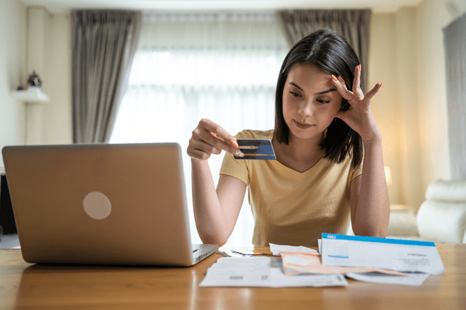 Woman looking at credit card stressed