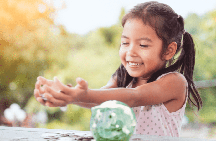 Little girl with green piggy bank