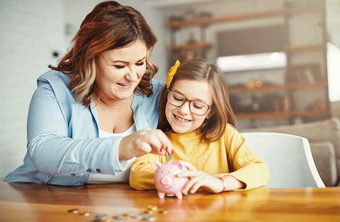Mom and child putting money into piggy bank