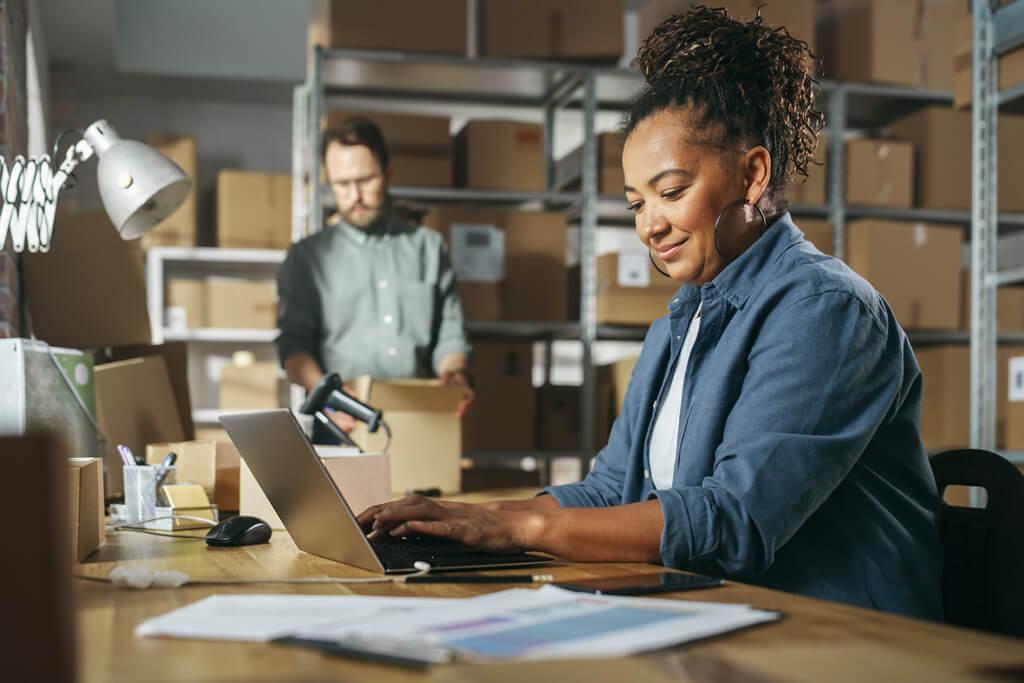 Woman on laptop in warehouse