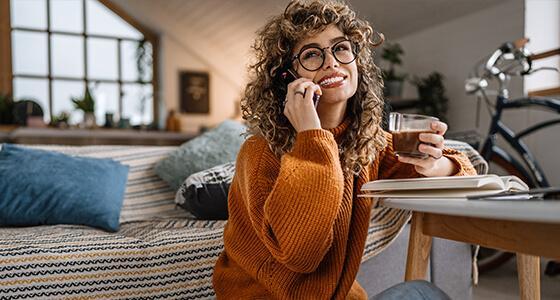 Woman sitting while on the phone and holding coffee