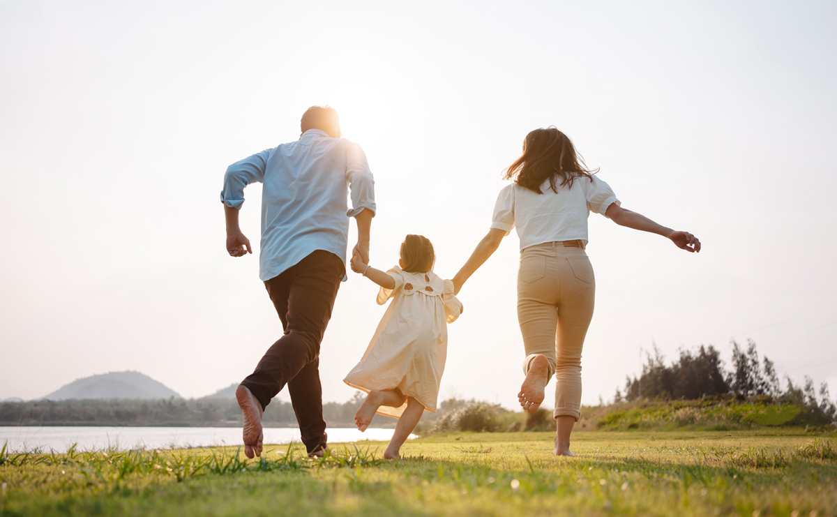 Family skipping on the field by the lake